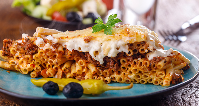 delicious baked pasta with meat and cheese served on a blue plate garnished with fresh herbs featuring seven unique flavors